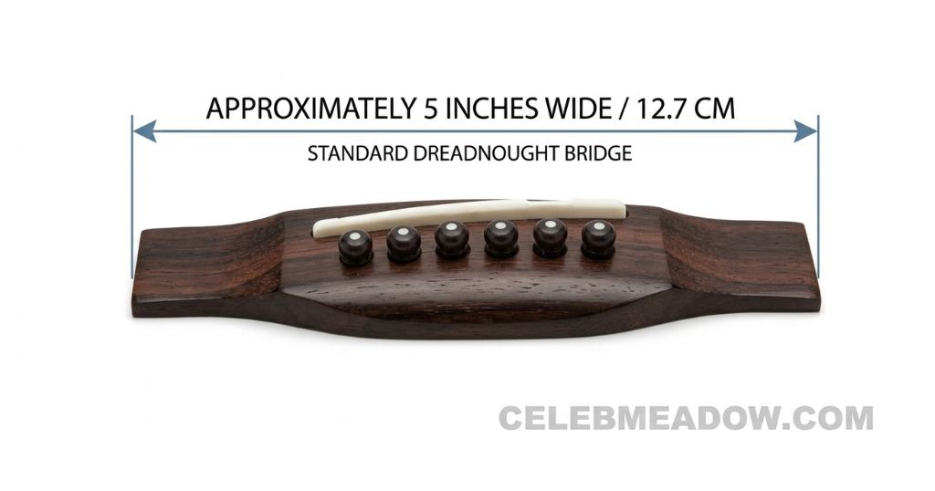 The wooden bridge of a standard dreadnought acoustic guitar showing 5-inch width where strings anchor